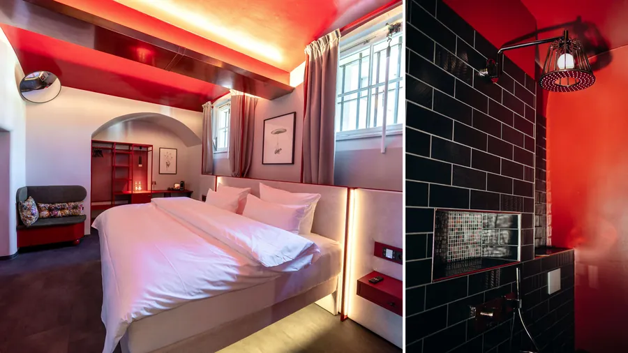Hotelzimmer im ehemaligen Gefängnis The Knast in Berlin mit roter Decke, daneben eine Dusche mit AXOR LampShower und schwarzen Fliesen