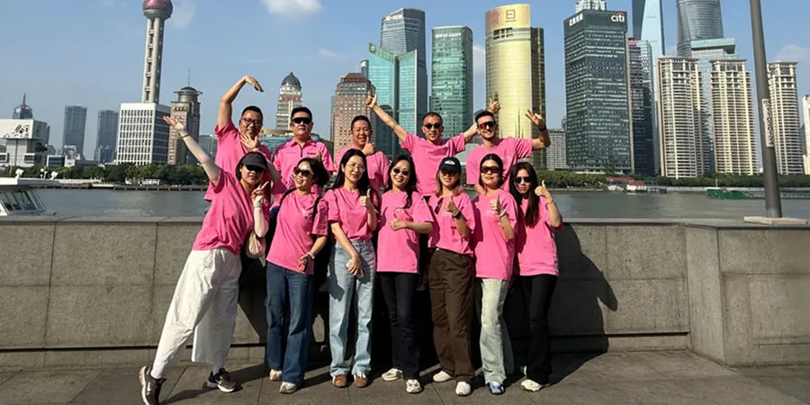 Gruppe in pinken Shirts des BWT Best Water Run 2026 vor einer Hochhaus-Skyline am Fluss