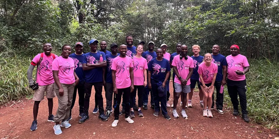 Gruppe in pinken und blauen Shirts des BWT Best Water Run 2026 auf einem Waldweg mit roter Erde